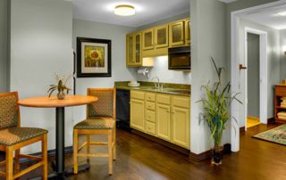 A kitchen with yellow cabinets and wooden floors.